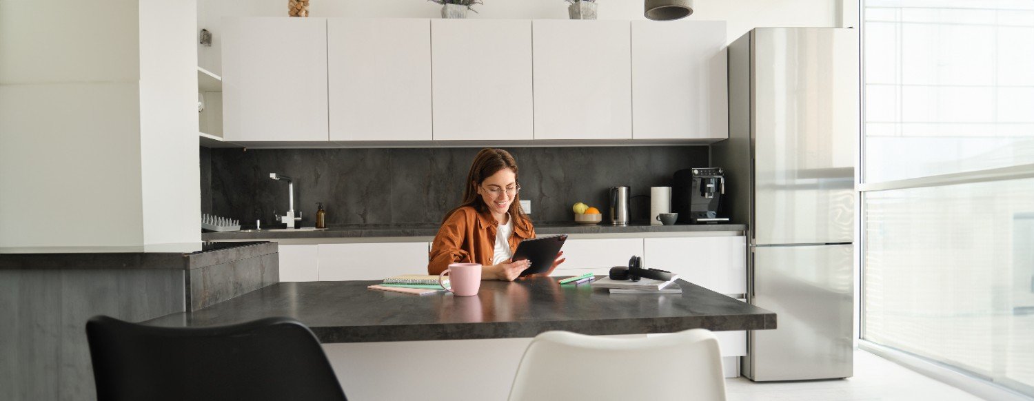 Smiling woman reading on a tablet at a modern kitchen island with white cabinets